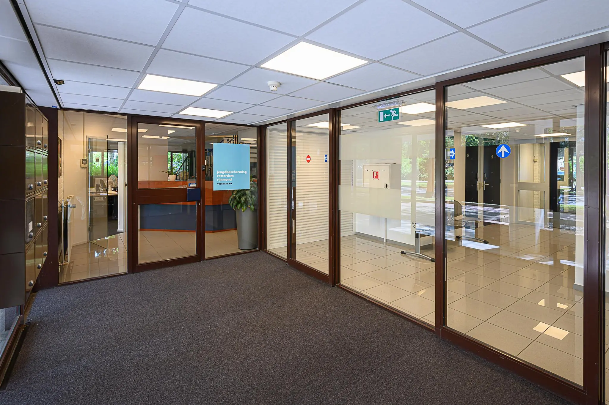 Ingang van het kantoor van Jeugdbescherming Rotterdam Rijnmond met balie en wachtruimte.